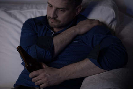 Lonely mature man drinking beer at eveningの写真素材