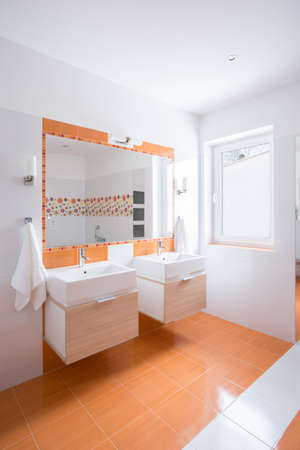 Bright bathroom with orange tiles and two basinsの写真素材
