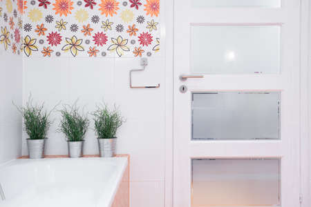 White entrance door to modern bathroom with floral decorationの写真素材