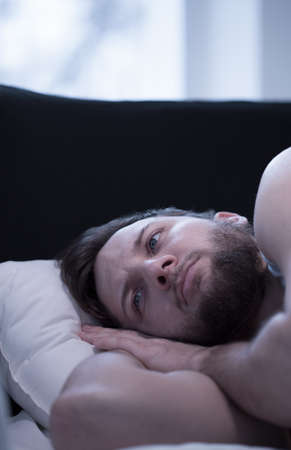 Close-up of young wake up man trying to fall asleepの写真素材