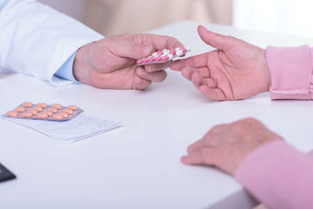 Close-up of doctor's hands giving patient medicamentの写真素材