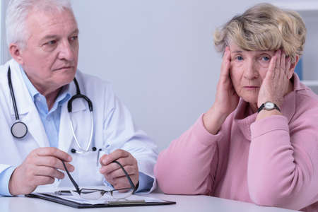 Image of worried senior woman in doctor's officeの写真素材