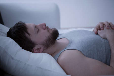 Close-up of young handsome man dozing in bedの写真素材