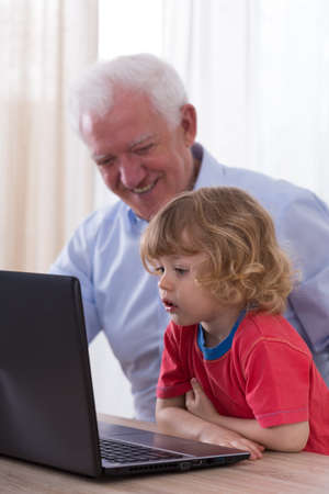 Image of grandfather and grandchild using laptopの写真素材