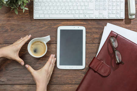 Woman catching cup of coffee from the deskの写真素材
