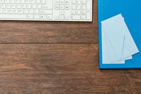 Three small envelopes and big folder on wooden deskの写真素材