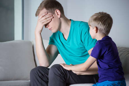 Depressed father sitting on couch with his son