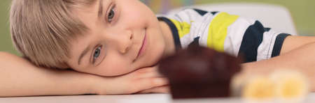 Panorama of cute boy and chocolate cupcakeの写真素材