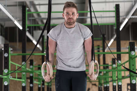 Athletic handsome man exercising on gymnastic circles