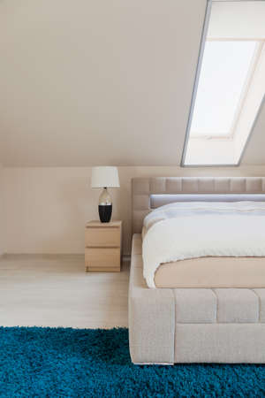 White bedroom with inclined wall and double bedの写真素材