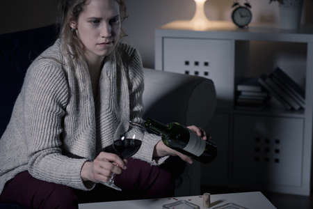 Image of troubled woman pouring red wineの写真素材