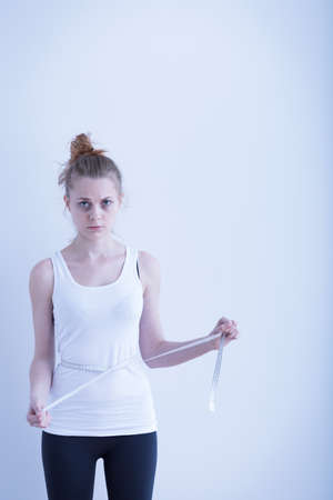 Image of anorexic girl measuring her waistの写真素材