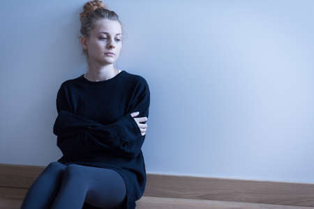 Young woman with anxiety disorder sitting on the floorの写真素材