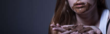 Young woman with bulimia nervosa eating chocolateの写真素材