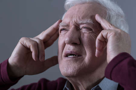 Old man holding his temples with opressive pain