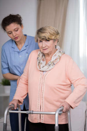 Female carer helping older woman with handicapの写真素材