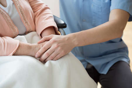 Nurse holding hands of a woman on a wheelchairの写真素材