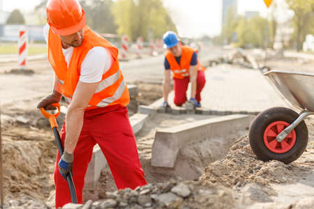 Two hard working builders in uniforms putting pavementの写真素材