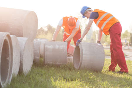 Two busy strong workers setting concrete circlesの写真素材