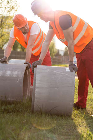 Two busy builders and heavy concrete pipesの写真素材
