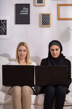 Girls sitting on the sofa with laptopsの写真素材