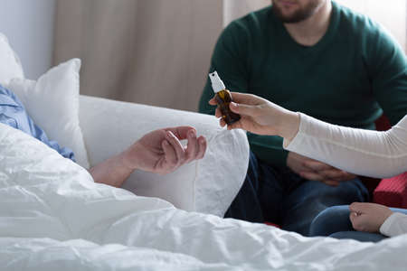Daughter giving the spray to sick father in hospitalの写真素材