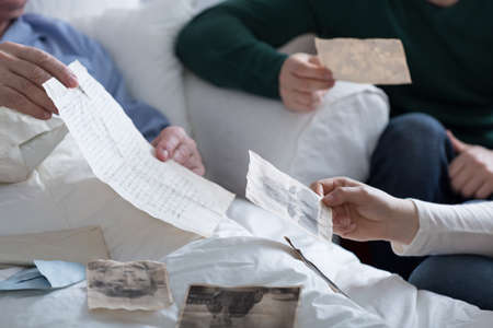 Close-up of adult children browsing father's old photosの写真素材