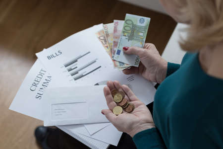 Elderly woman counting money and solving financial difficultiesの写真素材