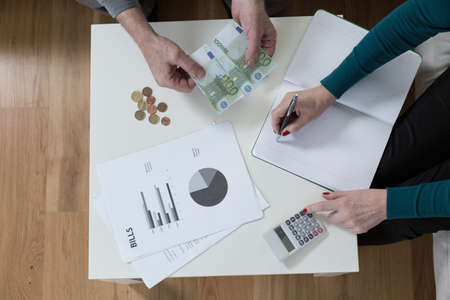 Sitting at a wooden table and solving financial problemsの写真素材