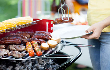 Closeup of woman dishing out grilled sausageの写真素材