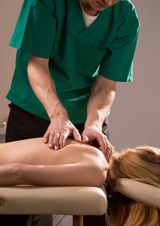 Physiotherapist pressing painful points on woman's back