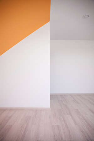 Unfurnished bedroom with white and orange walls and wooden floorの写真素材