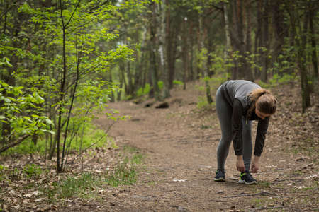 Female runner taking rest for tying shoes