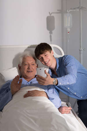 Older sick man and his grandson and video conference online