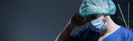 Worried male doctor after surgery striping the protective maskの写真素材