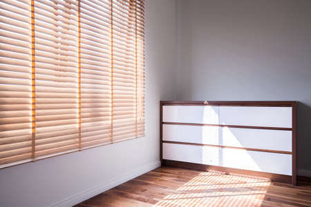 White and wooden commode in empty bright roomの写真素材