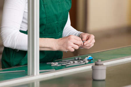 Close-up of older woman's hand turning the screws in factoryの写真素材