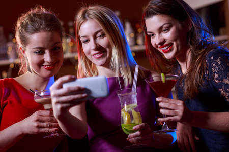 Beautiful young girls are taking selfie in the barの写真素材