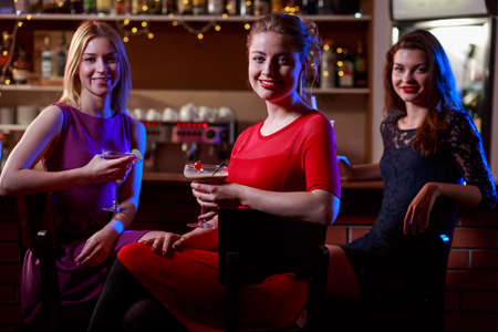 Beautiful friends are drinking in the nightclubの写真素材