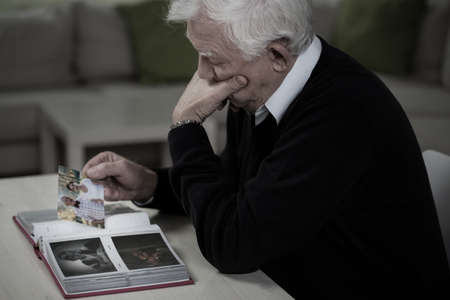 Widower looking at the photos and remembering deceased wifeの写真素材