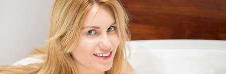 Blonde woman sitting in bathtub,panoramaの写真素材