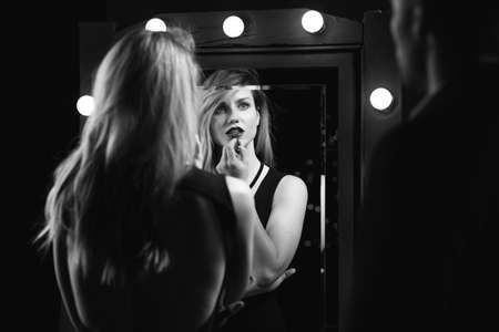 Image of an erotic woman applying lipstick