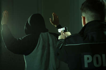 Image of a police officer keeping gun on a crookの写真素材