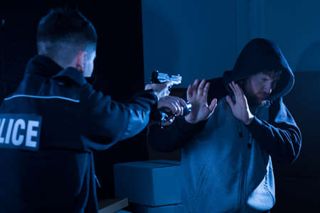 Image of criminal with gun aiming at him giving upの写真素材