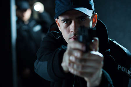 Close up of an armed policeman pointing pistolの写真素材