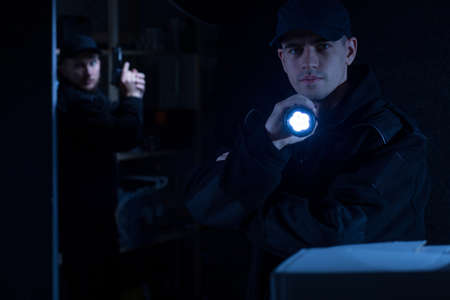 Photo of a young policeman holding flashlight during actionの写真素材