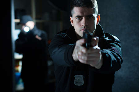 Image of a confident handsome policeman holding a handgunの写真素材