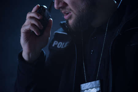 Young police officer reporting situation on the radioの写真素材