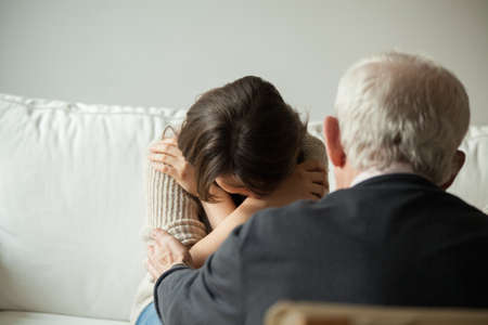Horizontal view of grandpa comforting his crying granddaughterの写真素材