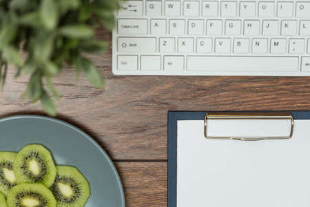 Close-up of desk office with kiwi, keyboard and notebookの写真素材